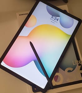 Samsung Galaxy Tab S6 Lite with the pen laying on the screen. The tablet is laying on the box the Samsung Galaxy Tab S6 Lite came in.