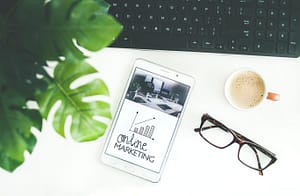 Top view of a desk with a keyboard, plant, glasses, cup of coffee, and a tablet that says "Affiliate Marketing for Beginners".