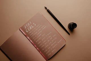 Notebook with a list of goals written in it. Achieve Your Goals
