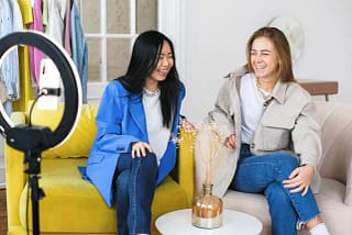 Women sitting laughing while filming a video