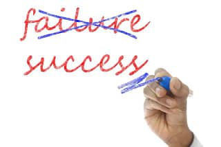Sign with a hand crossing out "failure" and underlining "success" Achieve Your Goals