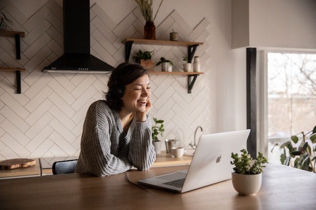 Woman sitting in front of her laptop smiling while reading.