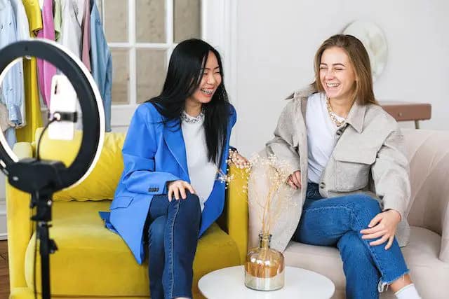 Women sitting laughing while filming a video