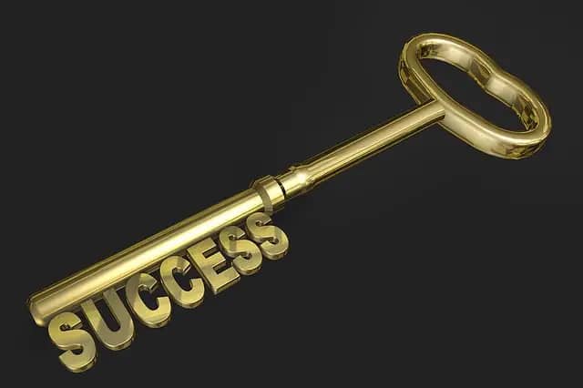 A gold key with the word success on it